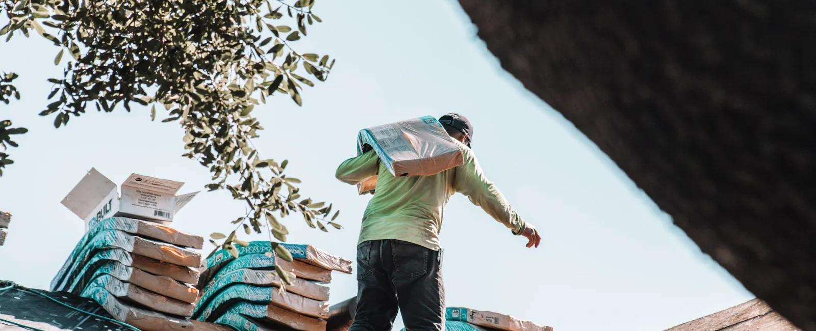 Roofer carrying a bundle of shingles onto a roof