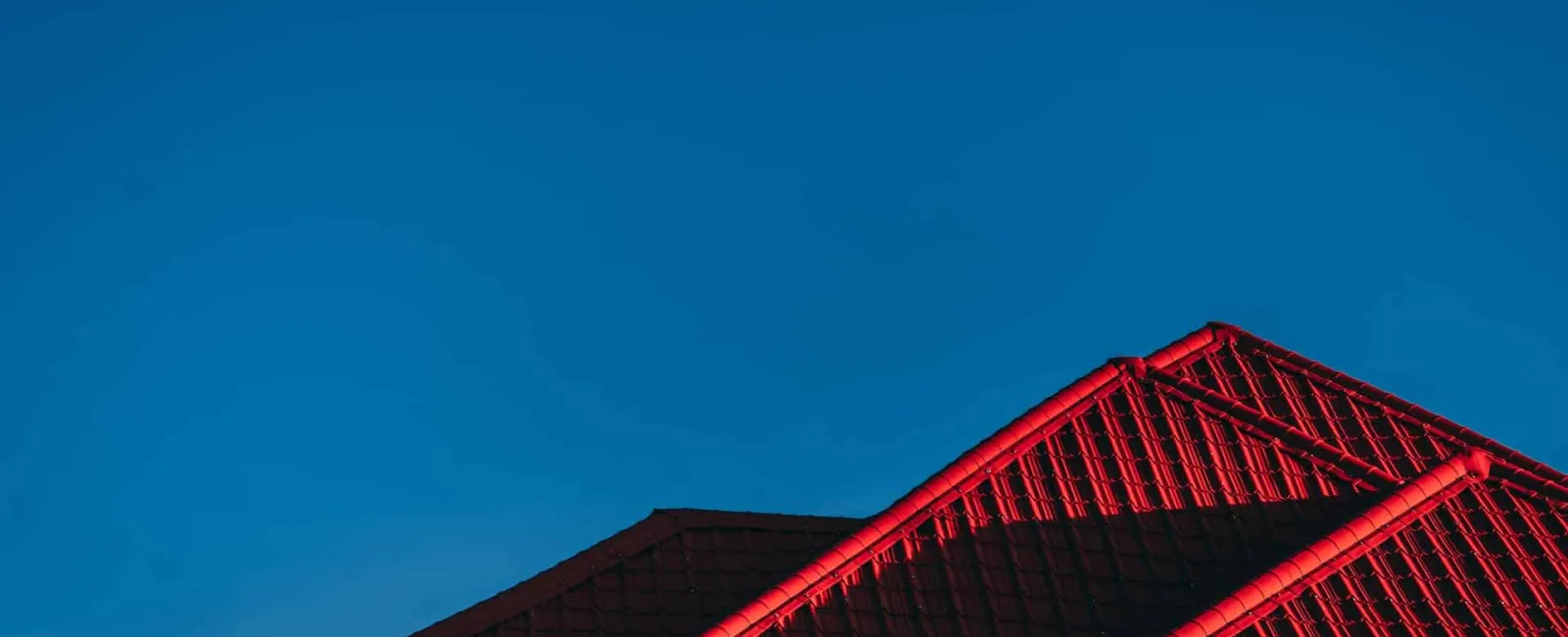 Red metal roof against a deep blue sky