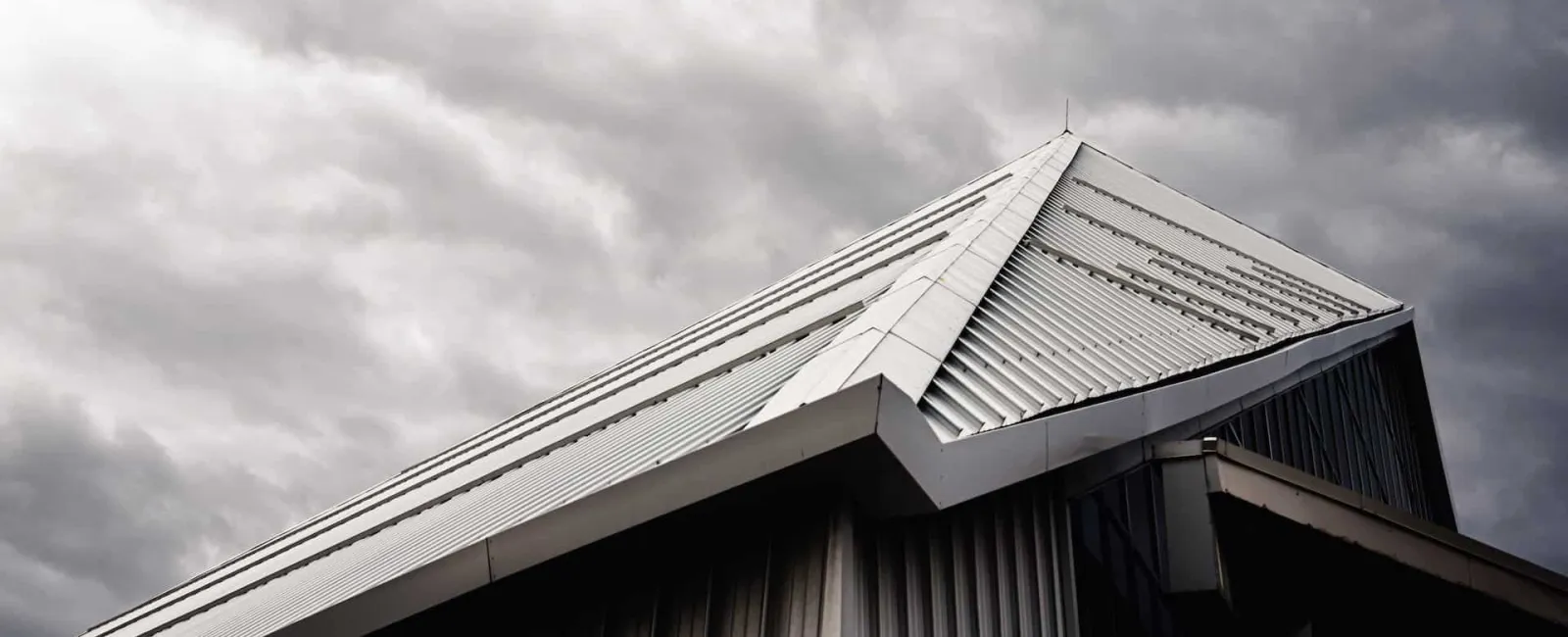 Metal roof ridge against a stormy sky