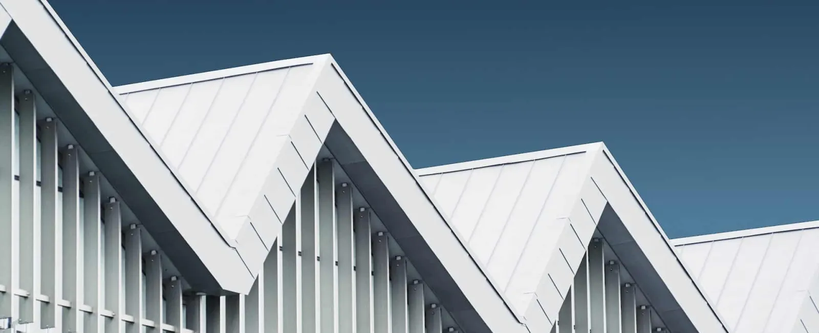White sawtooth metal roof against a blue sky